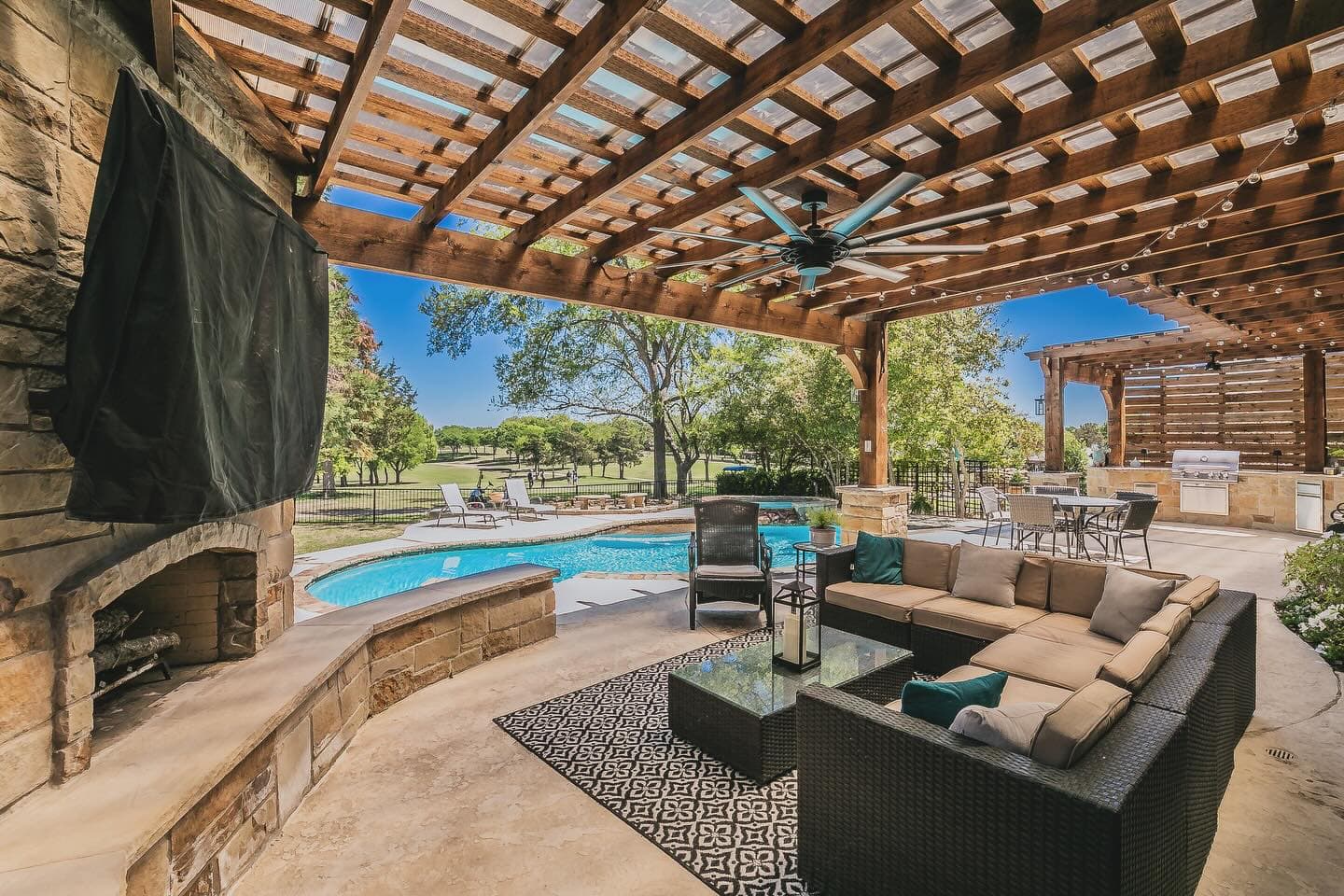 Completed Summerwood backyard with stone fireplace, pergola-covered lounge, and pool